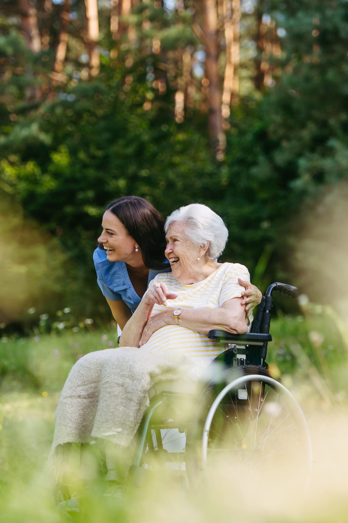 Betreuungskraft von Helfen mit Herz mit einer Seniorin im Rollstuhl bei einem Spaziergang