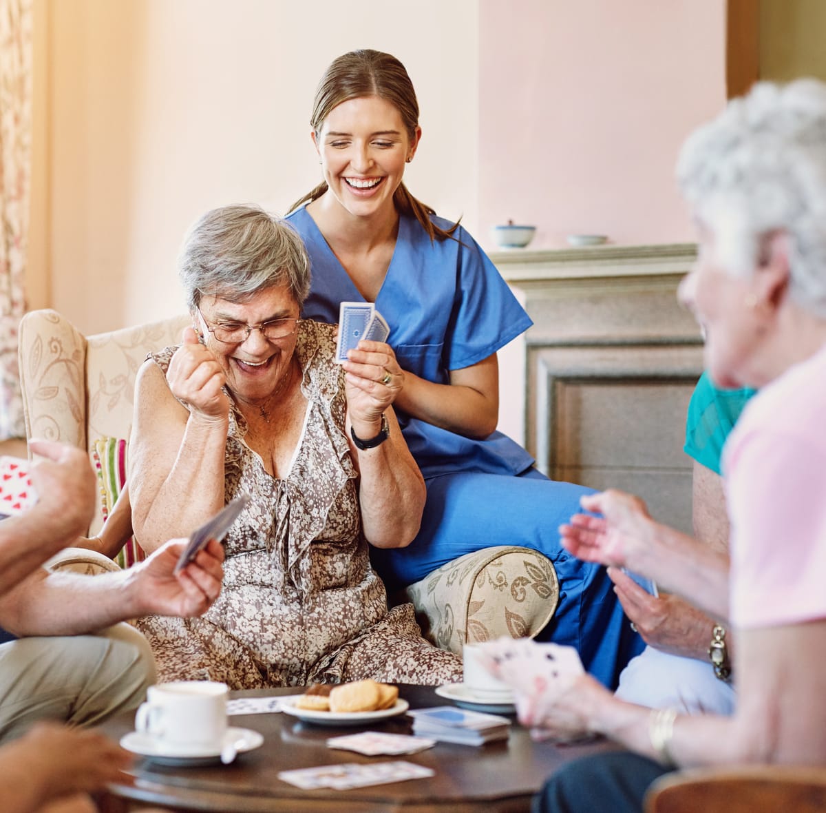 Betreuungskraft spielt Karten mit Seniorinnen und Senioren